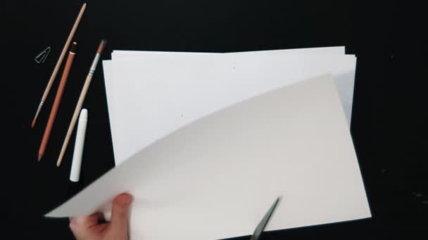 Tattooed female hands cuts heart shape out of white paper sheet using scissors — Stock Video