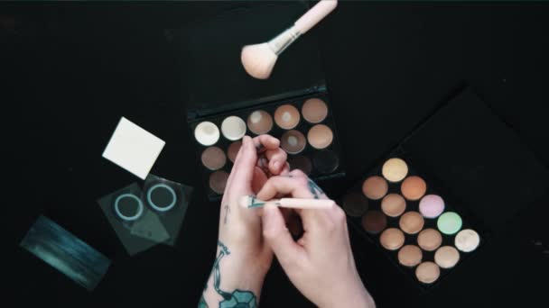 Wytatuowane kobieta ręce tryes proszku eyeshadow brush makijaż czarny stół — Wideo stockowe