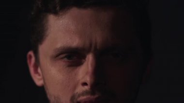 Genç adam sakal ve kıvırcık saçlı gülümsüyor ve frowns kameraya endişe.