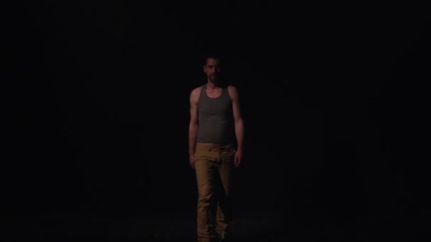 男人在短期灰色背心和黄色裤子走和开始脱衣服 — 图库视频影像