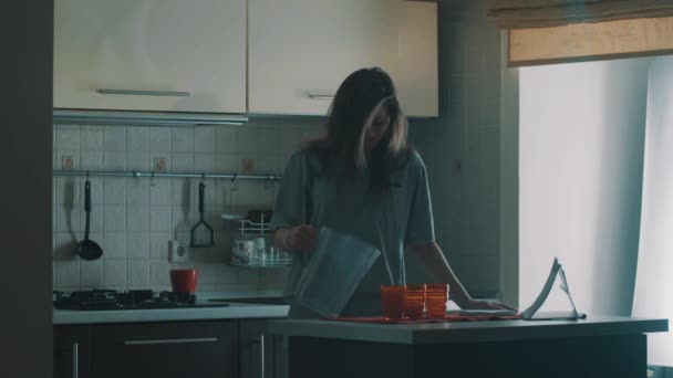 Дивна дівчина з порожнім глечиком ковзає і падає на підлогу на кухні вранці — стокове відео