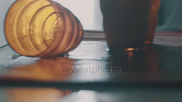 Orange glass rolls over edge of wet kitchen table in early morning — Stock Video