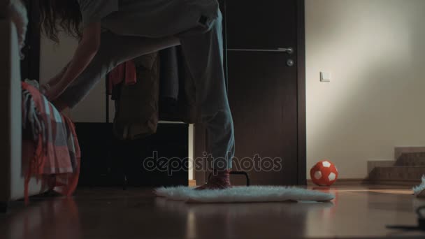 Молодая гибкая девушка в гостиной поскальзывается на ковре и случайно делает шпагат — стоковое видео