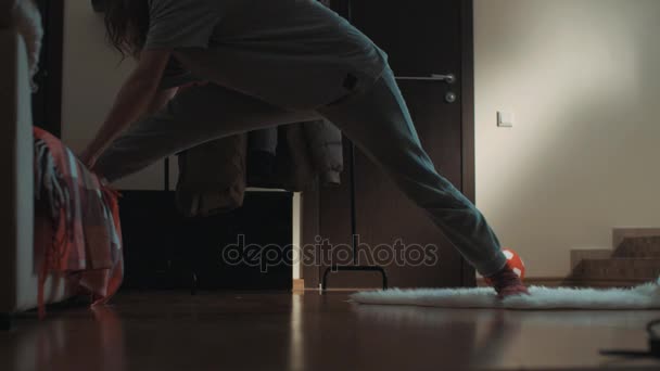 Молода гнучка жінка у вітальні ковзає на килимку і випадково робить розщеплення — стокове відео