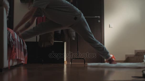 Chica morena joven en la sala de estar se desliza en la alfombra y se extiende a través del piso — Vídeo de stock