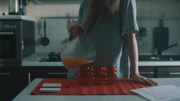 Onhandige brunette vrouw gieten van sinaasappelsap in rood glas, morsen het overal — Stockvideo