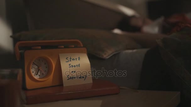 Reloj despertador de radio amarillo en la mesa de la cama con etiqueta motivadora en él — Vídeo de stock