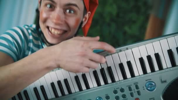 Hombre divertido vestido como enano barbudo espeluznante sonriendo y toca sintetizador — Vídeo de stock