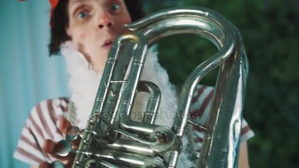 Joyful man in dwarf costume blown up cheeks playing old weary broken tin tuba — Stock Video