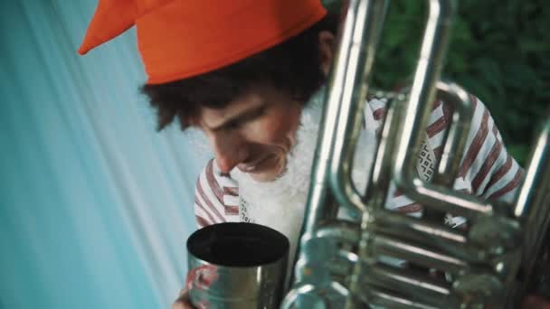 Vrolijke man in dwerg kostuum schreeuwt aan gebroken tin tuba, blijkt dat in camera — Stockvideo