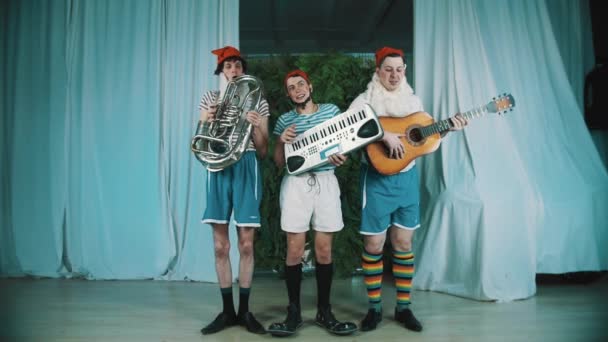 Três homens engraçados vestidos de anões tocando instrumentos musicais em cena — Vídeo de Stock