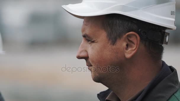 Slowmotion portret προφίλ ανδρών στο λευκό σκληρό καπέλο στο κτίριο τραβήξτε εστίαση ιστοσελίδας — Αρχείο Βίντεο