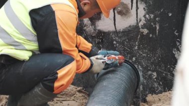 Oluklu plastik boru ve beton delik arasında dikiş dolgu macunu uygulayarak işçi