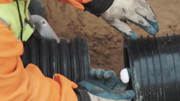 Il lavoratore strizza l'adesivo sul dito nel guanto e lo applica sul bordo del tubo di plastica — Video Stock