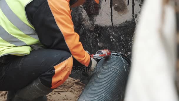 Builder applying sealant on stitch between ribbed plastic tube and concrete hole — Stock Video