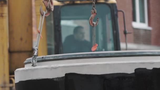 Excavadora de pie en el sitio de construcción con anillo de alcantarilla de hormigón balanceo en cadenas — Vídeo de stock