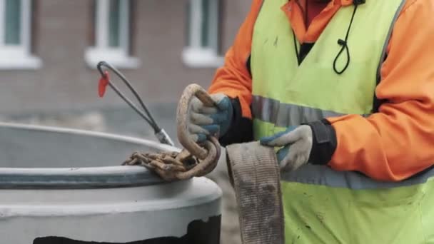 Рабочий привязал длинную ленту к металлической цепи петли на строительной площадке — стоковое видео