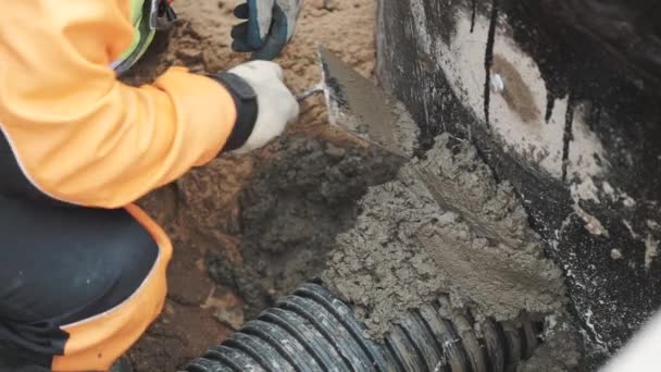 Werknemer in de zegel steek geribbeld plastic pijp en concrete gat met cement spatel — Stockvideo