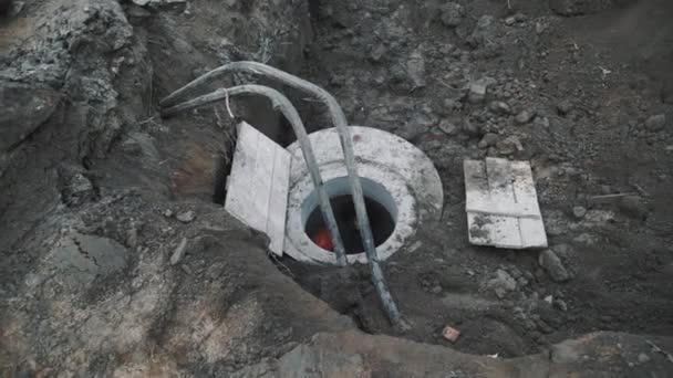 Trabajador en sombrero duro naranja en alcantarilla de cámara de hormigón en el sitio de construcción de alcantarillado — Vídeo de stock