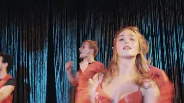 Женщина в костюмах красных креветок в морской тематике танцует на сцене с двумя парнями — стоковое видео