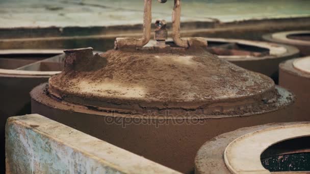 Pracovník pomocí průmyslového jeřábu vytáhnout kovovou kotel z betonový prstenec v továrně — Stock video