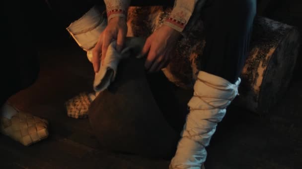 Male hands in historical russian costume cleaning soot pot with piece of cloth — Stock Video