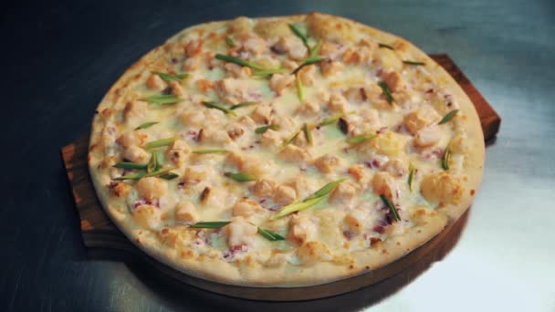 Pizza de aspecto sabroso con cebolla en plato de madera sobre mesa de metal escritorio en la cocina — Vídeos de Stock