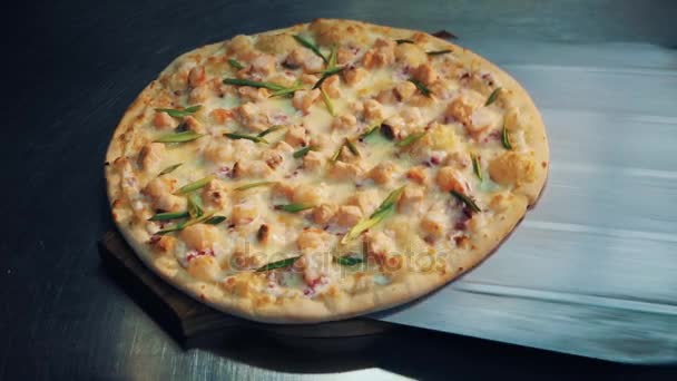 Ferramenta de pá colocar pizza em placa de madeira sobre mesa de metal, as mãos femininas levá-lo embora — Vídeo de Stock