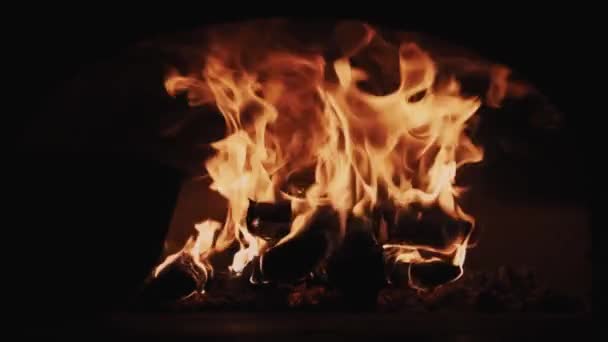 Llamas de fuego rojo ardiendo troncos en la chimenea habitación oscura — Vídeo de stock