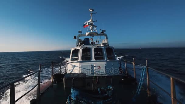Bateau à moteur avec drapeau russe passant rapidement sur l'eau de l'océan sous un ciel clair — Video