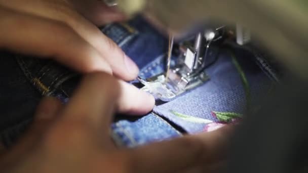 Les mains de tailleur féminin utilisent une machine à coudre pour coudre le patch avec une image rose pour denim — Video