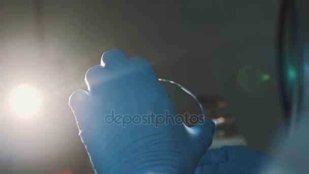 Вчений зачиняє скло ватним тампоном в лабораторії в яскравому ламповому світлі — стокове відео
