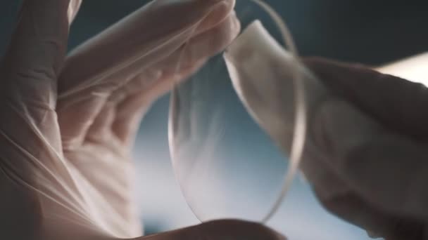 Hands in white rubber gloves cleaning round glass lens using cloth piece — Stock Video