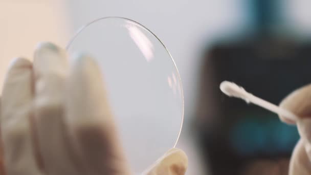 Scientifique en gants de caoutchouc nettoyage loupe verre lentille contre la lumière — Video