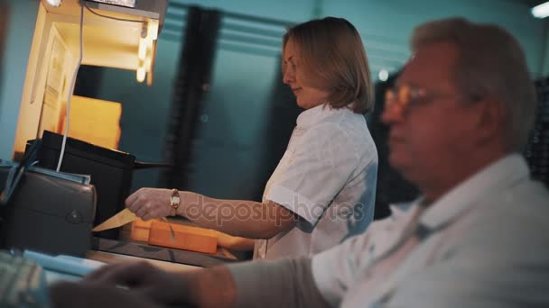 Woman in white robe put stickers on plastic trays in laboratory — Stock Video