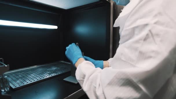 Opticien beheert lenzen in metalen verlichte vak laboratorium — Stockvideo
