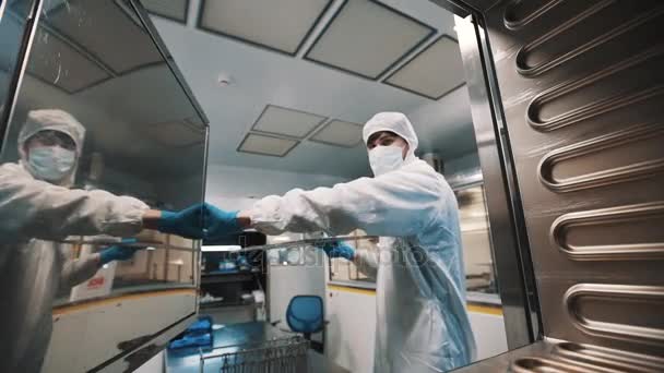 Forskare i fara sterila kostym sätta plåt inne laboratoriet ugnen — Stockvideo