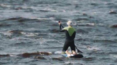 Tam mayo oturuşta sporcunun raket rüzgarlı bir günde kullanarak sörf tahtası rides