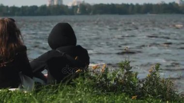 Olarak sörfçünün oynamaya Gölü arasında gezintisi çimenlerin üzerinde oturan çift izle