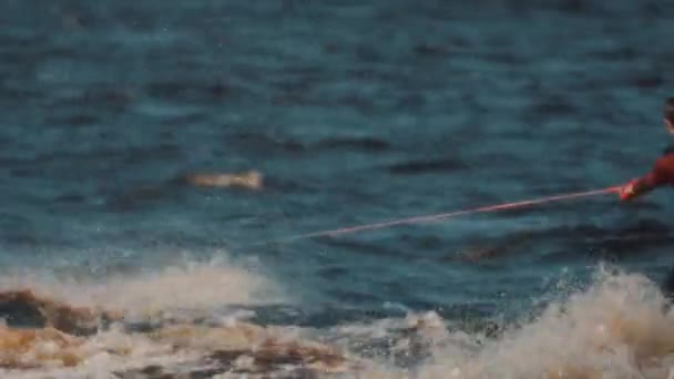 Surfer auf einem Wakeboard auf einem Wasser, das von einem Jetski mit gespannter Schnur gezogen wird — Stockvideo
