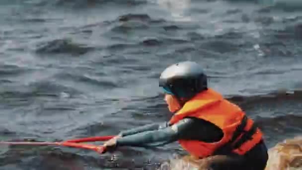 Close up de um menino em um wakeboard puxado para fora da água com corda esticada — Vídeo de Stock