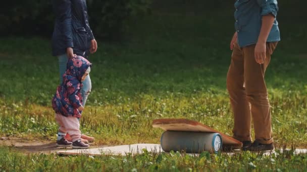 Mère tenant la main de l'enfant que le père tente d'équilibrer sur une planche sur cylindre — Video