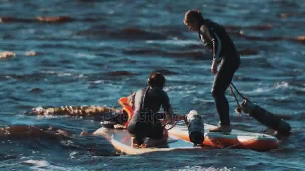 Chica surfistas golpeándose unos a otros con bastones suaves para empujar oponente en el agua — Vídeo de stock