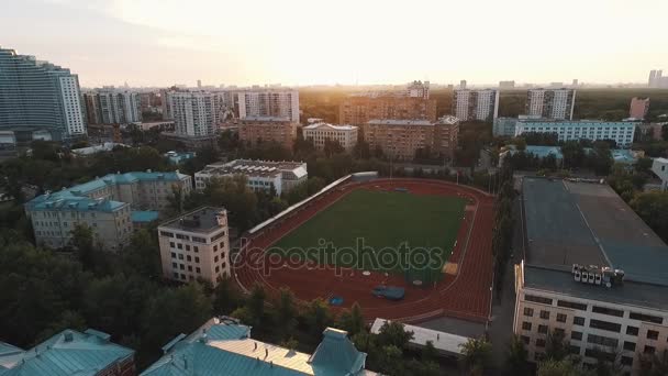 Vista aérea puesta de sol sobre el estadio de deportes en el área de dormitorio de la ciudad — Vídeos de Stock