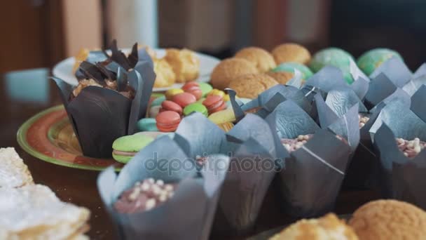 Suiker poeder pour op gelaagde taart op tafel met een heleboel bakken producten — Stockvideo