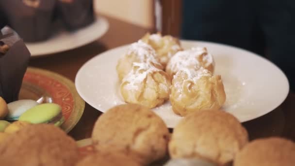 Pó de açúcar goteja em profiteroles na mesa com lotes de produtos de sobremesa — Vídeo de Stock