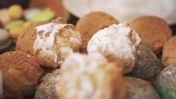 Ręka umieszcza profiteroles pokryte w proszku, cukier w stos na talerzu — Wideo stockowe