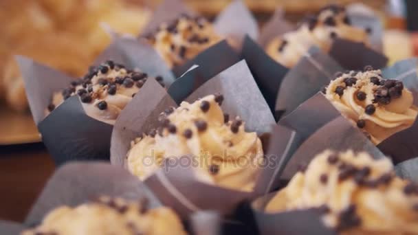 Copos de almendras gotas en los remolinos de mantequilla en mini pasteles en la panadería — Vídeo de stock
