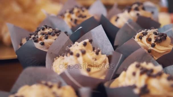 Le gocce di scaglie di mandorle su riccioli di crema di burro su mini torte in panetteria — Video Stock