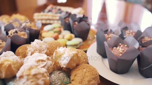 Deliciosos alimentos doces coloridos decorados na mesa antes da festa de chá — Vídeo de Stock